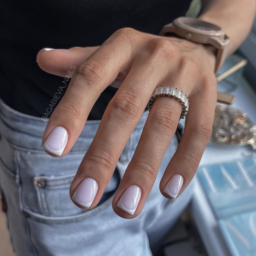 Short square nails with milky base and white French tips creating a soft spring aesthetic
