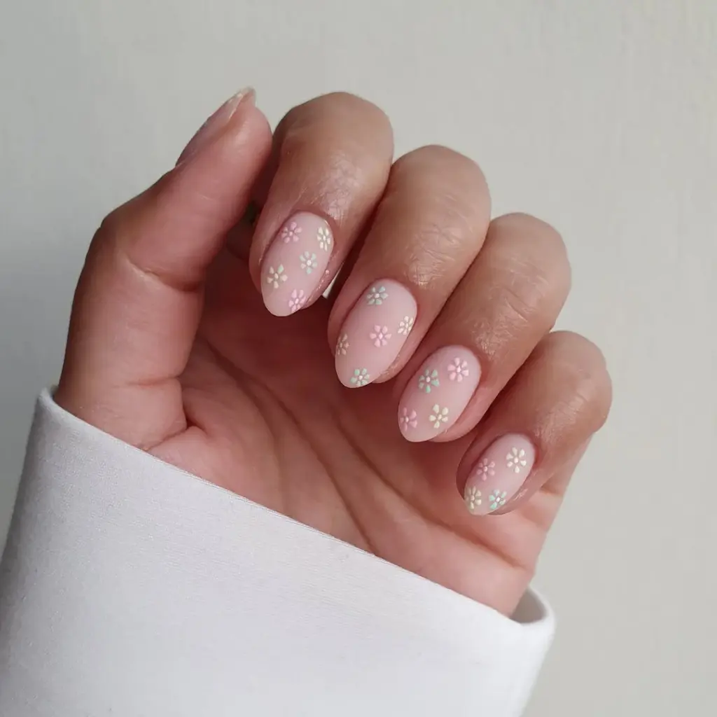 Almond shaped pink nails with small multicolored daisy flower pattern in white, blue and pink throughout
