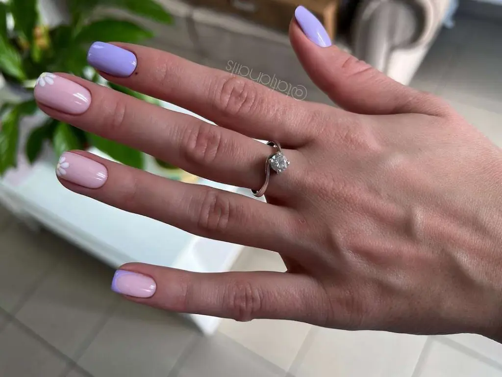 Short square nails in pastel skittles design with pink and lavender polish and white daisy details
