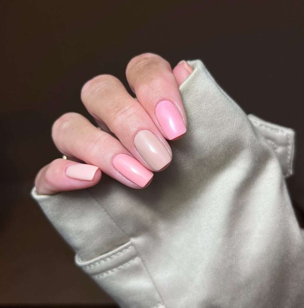 Short square nails with alternating pearl pink and nude polish in skittle design