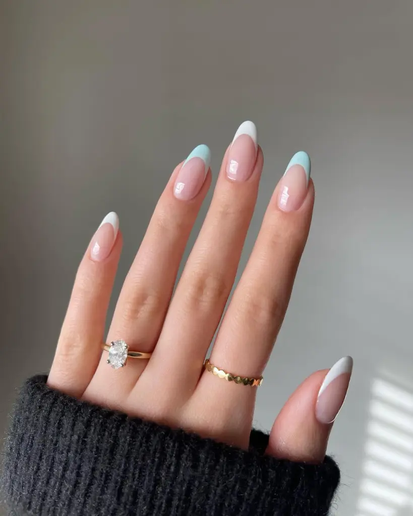 Almond-shaped elegant nails with glossy nude base featuring alternating white and baby blue French tips
