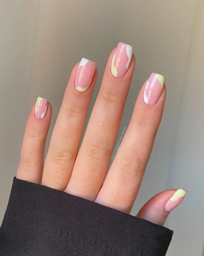 Short square pink nails with white and pale yellow abstract swirl designs
