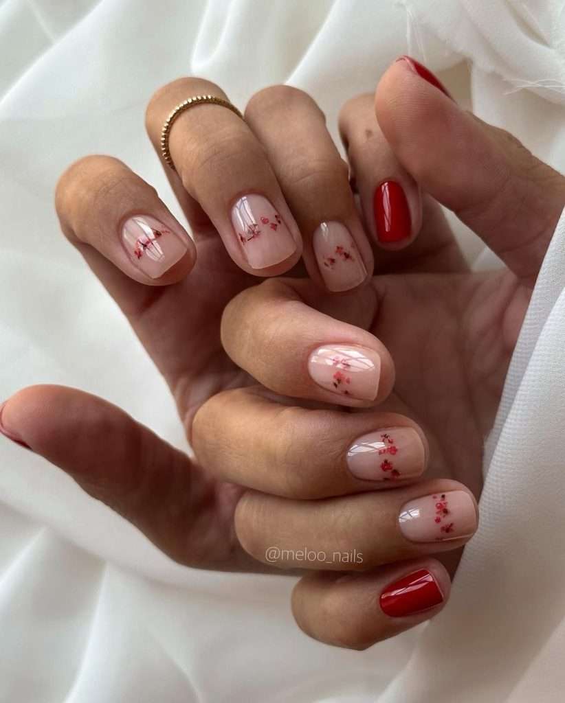 Short square nails with pink jelly base, dried pressed red flower details and glossy red polish accent nails