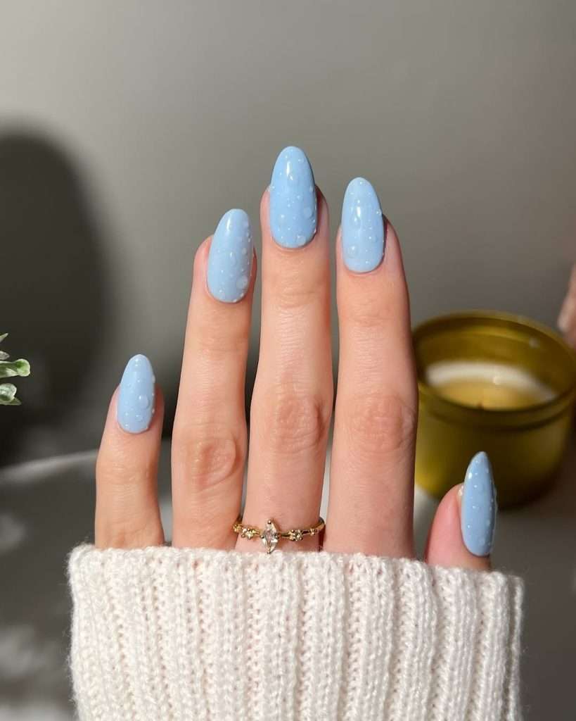 Long almond nails with light blue polish and clear dewdrop design
