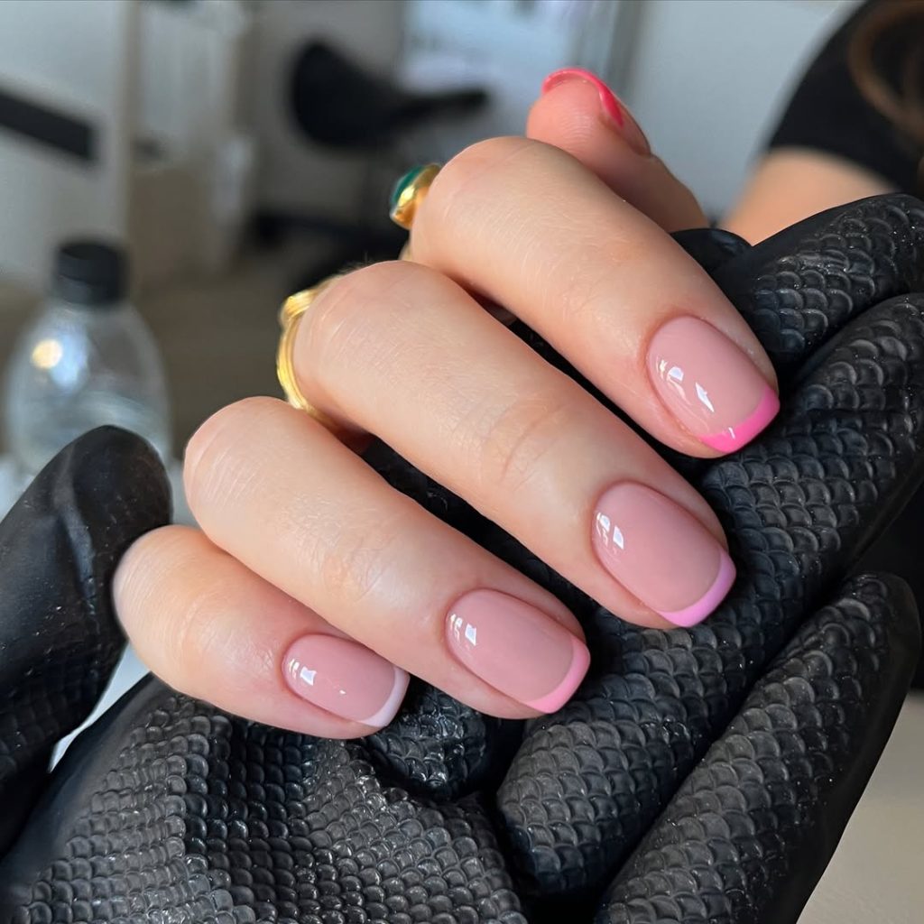 Short square nails with translucent pink base and thin hot pink French tips

