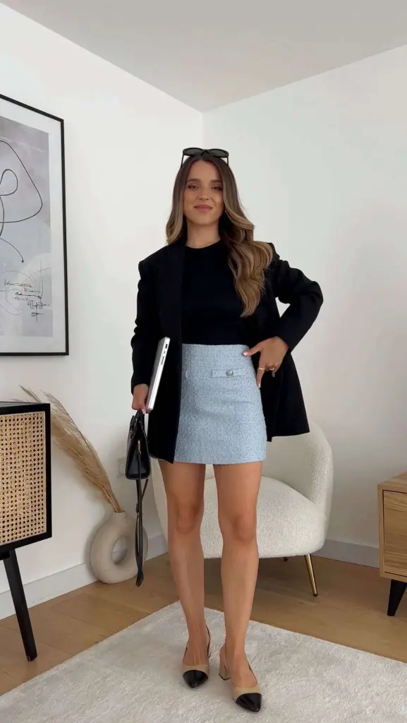Business casual outfit with black oversized blazer, black top, light blue tweed mini skirt, beige and black cap-toe heels and black structured handbag 