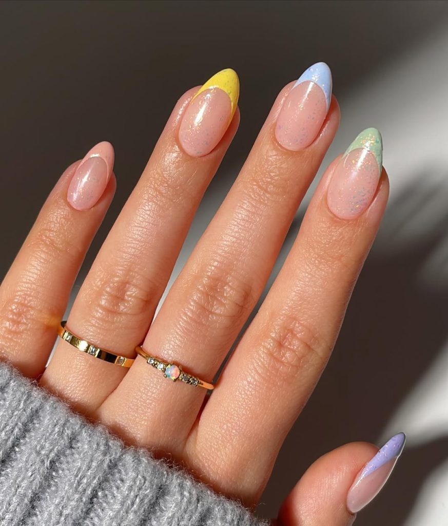 Almond-shaped nails with glittery nude base and multicolored French tips in mint, blue, yellow and pink, creating a dimensional spring look