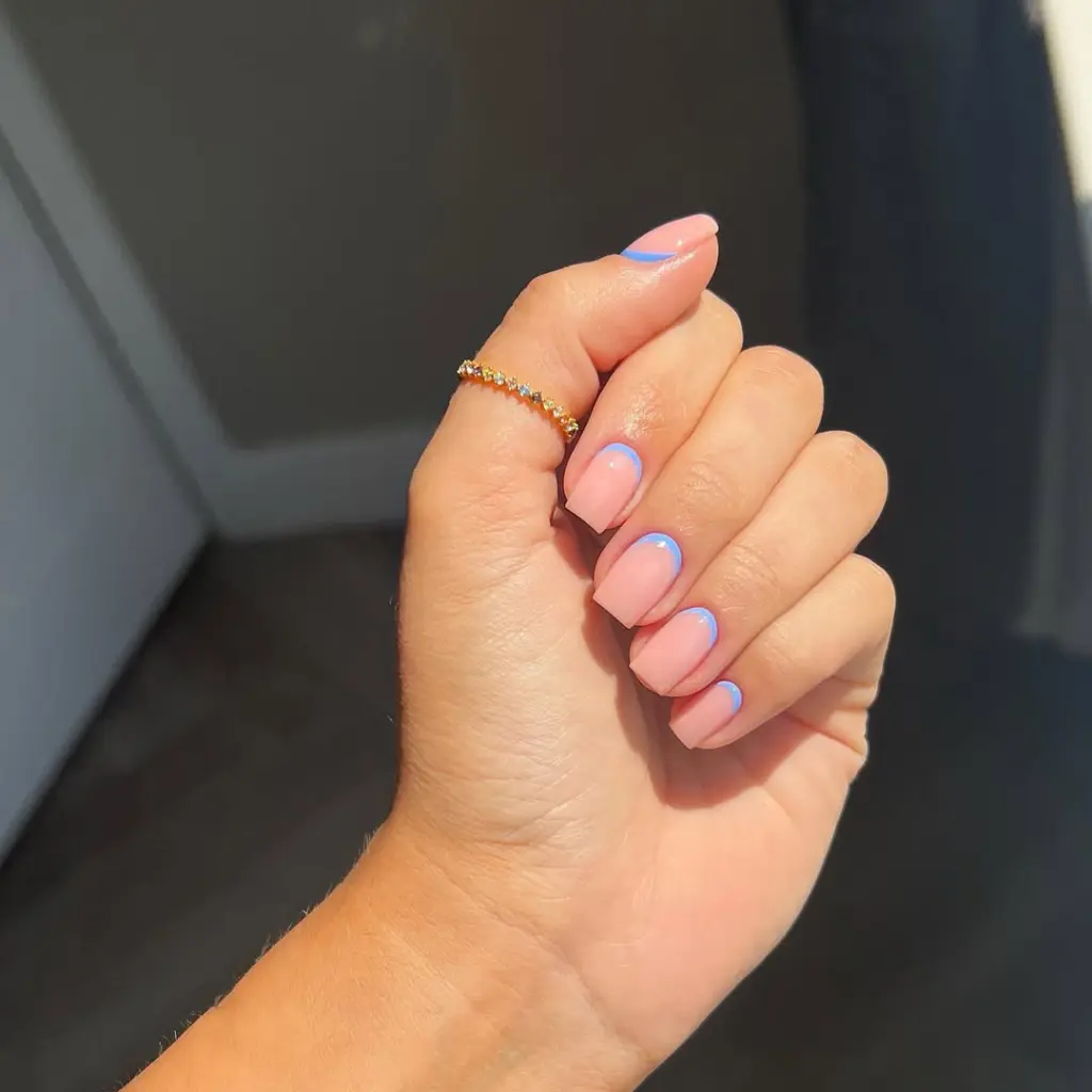 Short square pink nails with thin light blue curved accents at the nail base and matte finish
