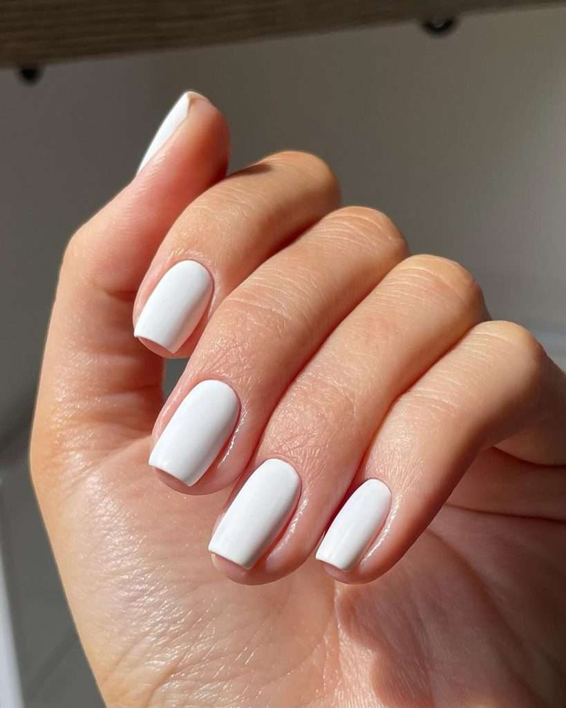 Short square nails painted in solid bright white polish