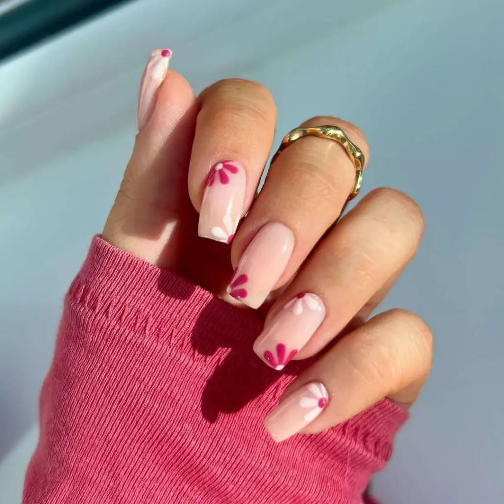 square nails with sheer pink base and magenta flower petal details
