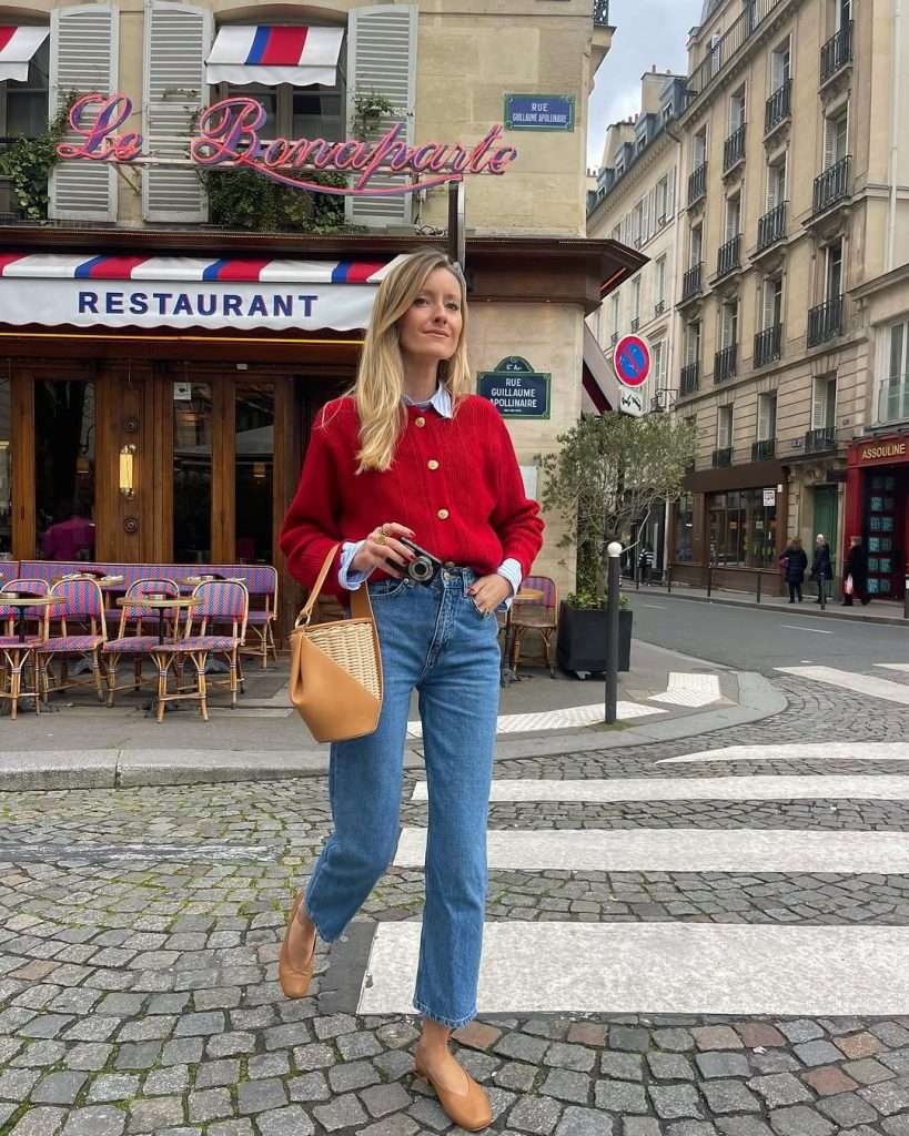 casual spring outfit with red button-up cardigan, white collared shirt, straight leg jeans, tan ballet flats and tan woven bucket bag
