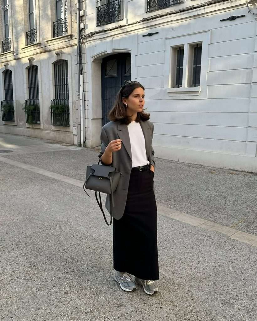 Minimal spring outfit with gray oversized blazer, white t-shirt, black maxi skirt, gray sneakers and black structured bag
