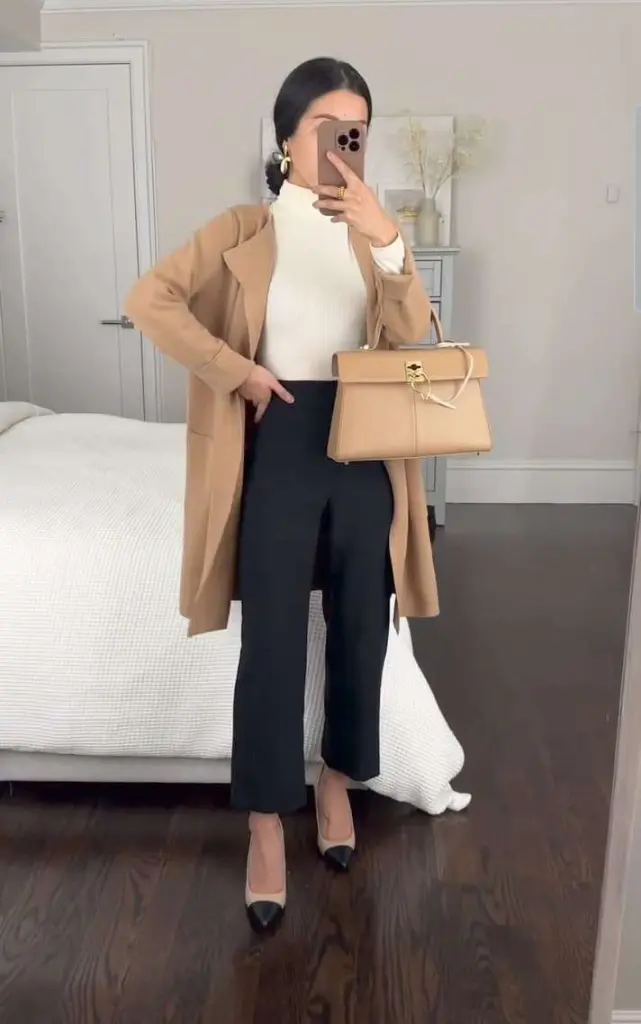 Business casual outfit with camel coat, cream turtleneck sweater, black straight-leg trousers, beige and black cap-toe pumps and matching beige structured handbag