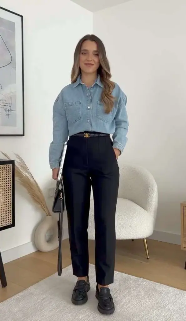 Business casual outfit with light blue denim shirt, black tailored trousers, designer belt, black loafers and black leather handbag 