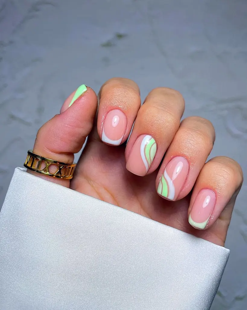 Short square nails with pink base, white French tips and green swirl accent designs