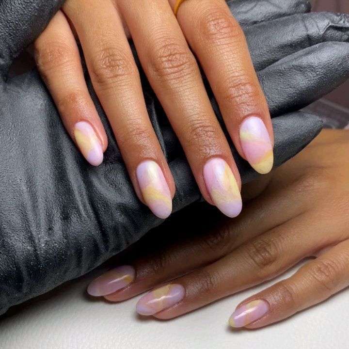 Medium almond nails with glossy watercolor effect in pastel pink and yellow aura pattern