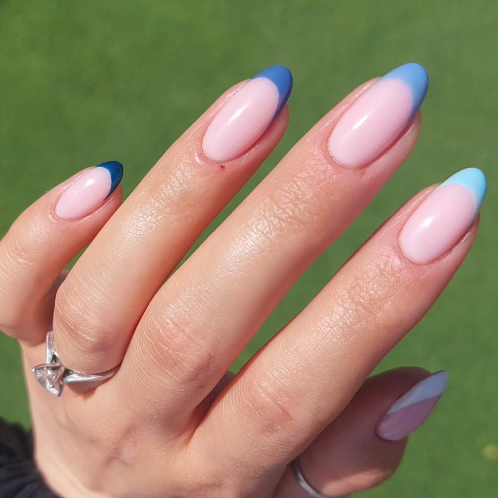 Oval-shaped pink nails with gradient blue French tips transitioning from navy to light blue, creating an elegant spring manicure