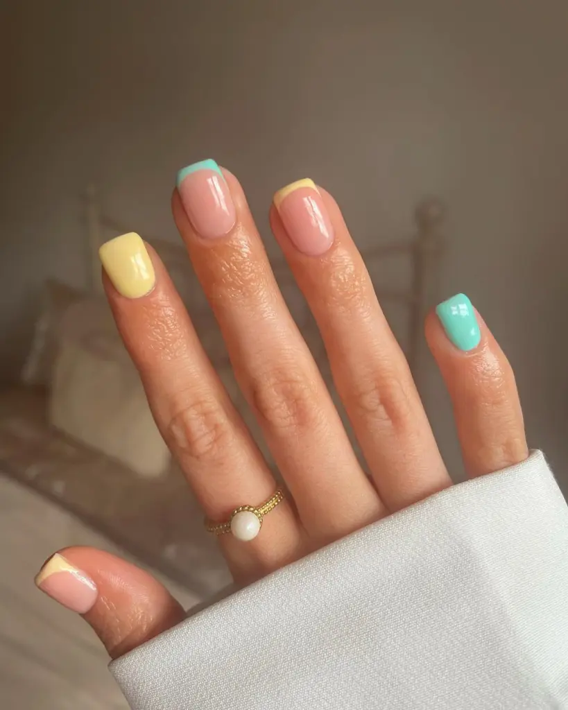 Short square spring nails in pastel colors with mint green tips, yellow accent nails and pink base with yellow and mint tips