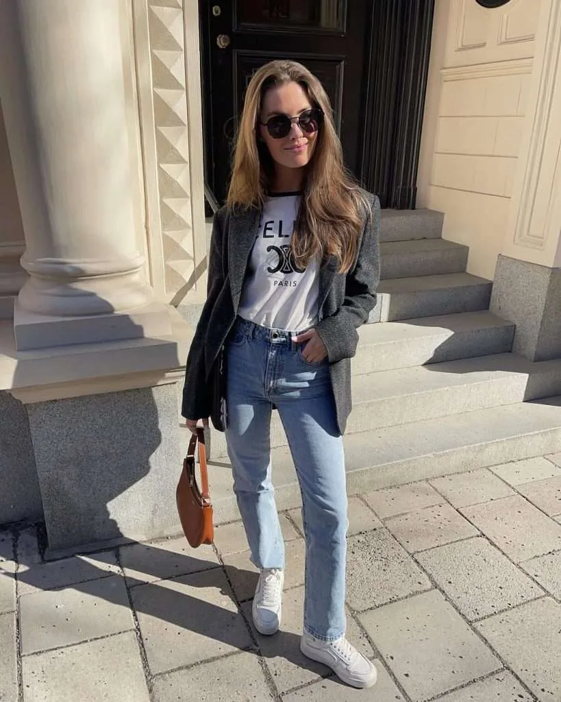 Classy spring outfit with grey oversized blazer, white Celine logo t-shirt, straight leg jeans, white sneakers and tan leather shoulder bag