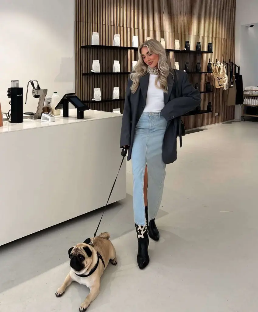 Classy spring outfit with black oversized blazer, white t-shirt, neck scarf, light wash denim maxi skirt, black cowboy boots and pug companion