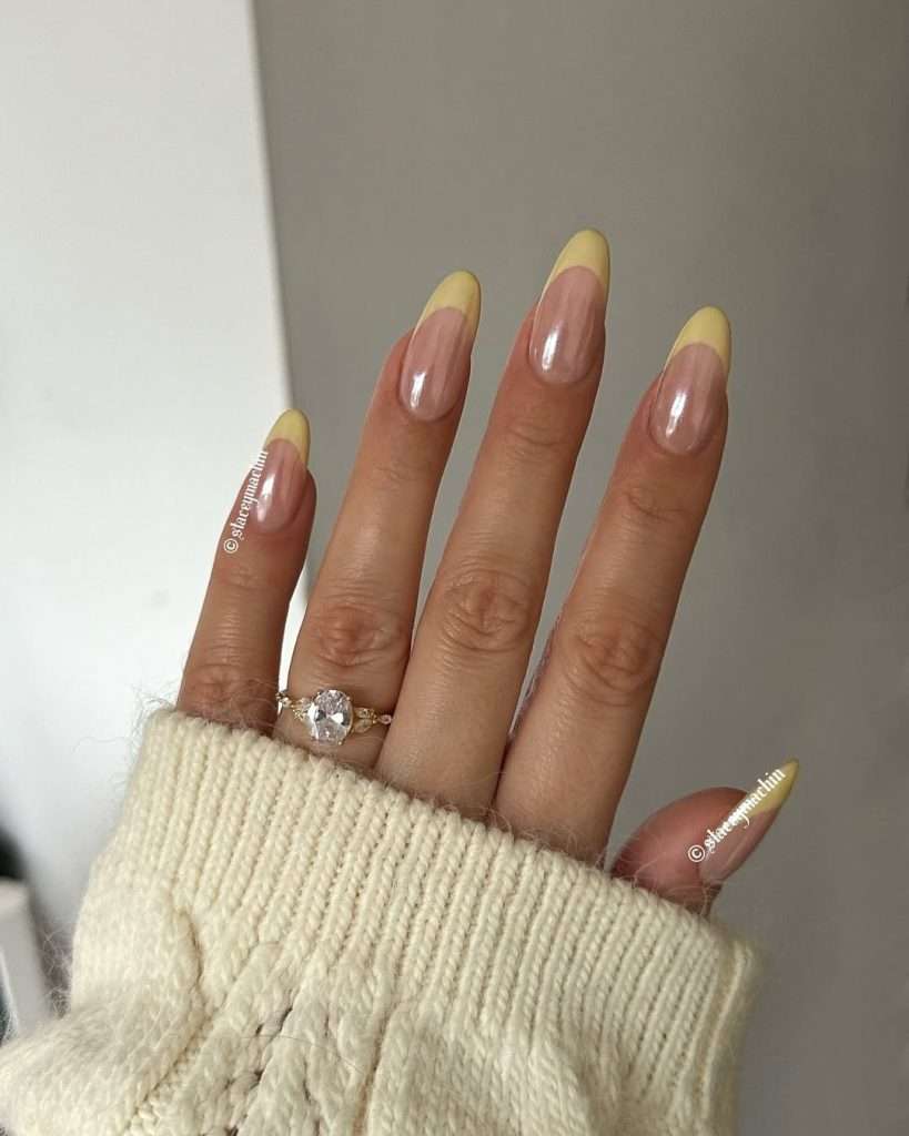 Long almond nails with glazed nude base and pastel yellow French tips