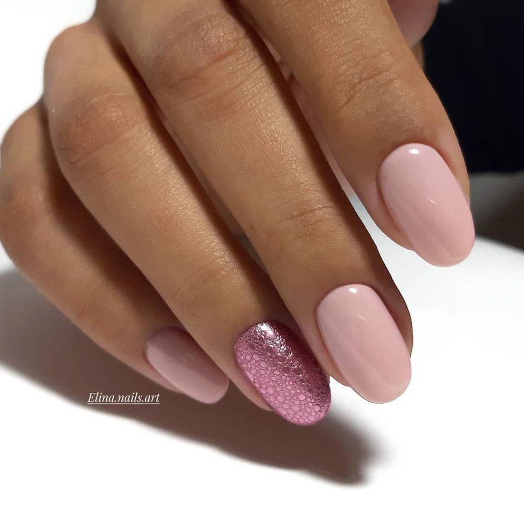 Short oval nails with pale baby pink polish and rose gold bubble texture accent on ring finger 