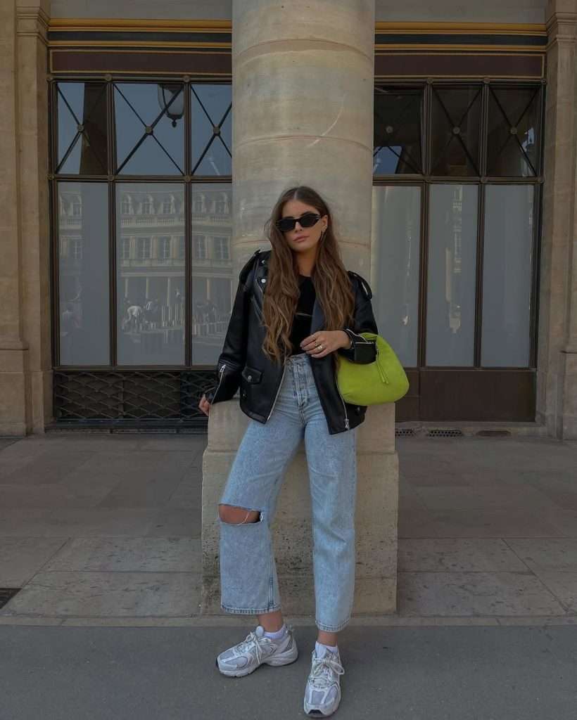 spring outfit with black leather jacket, black crop top, light wash ripped jeans, white sneakers and neon green shoulder bag