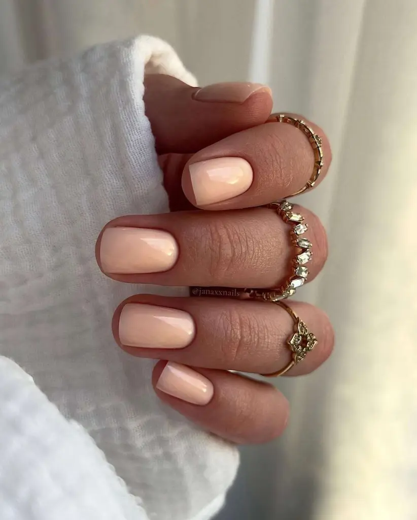 Short square nails in glossy peachy nude polish
