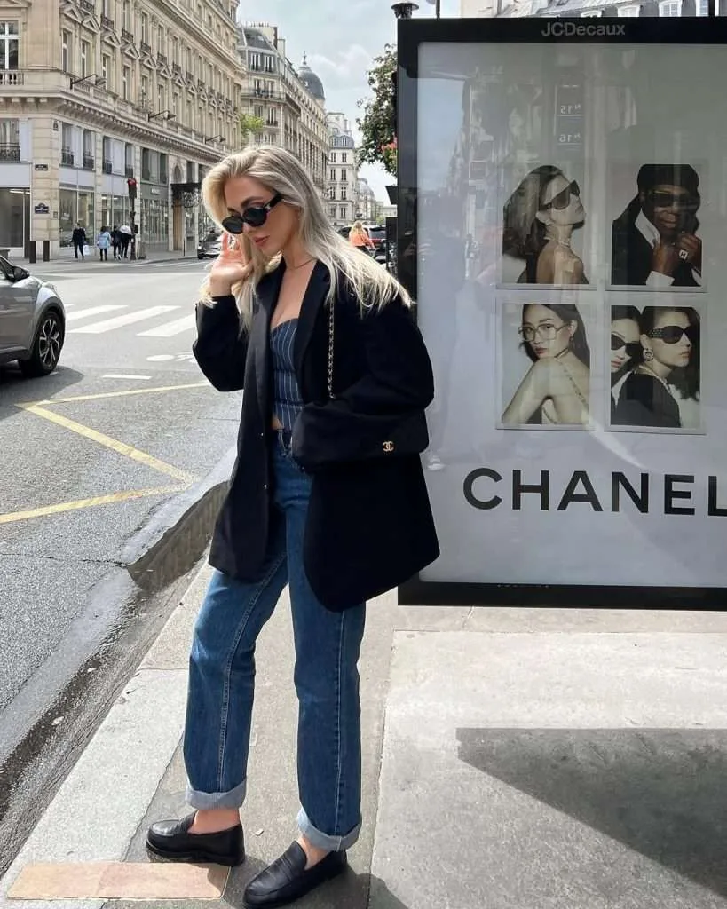 Classy spring outfit with black oversized blazer, navy pinstripe corset top, relaxed fit jeans, black loafers and Chanel crossbody bag
