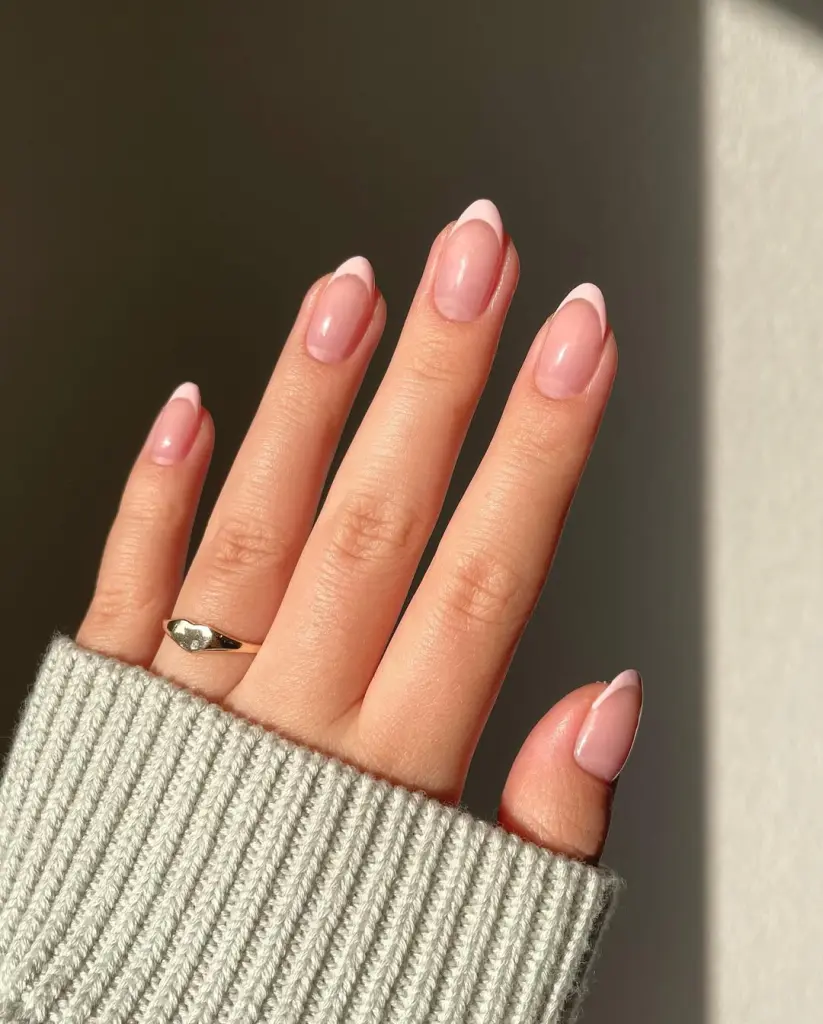 Almond-shaped nails with transparent nude base and delicate baby pink French tips
