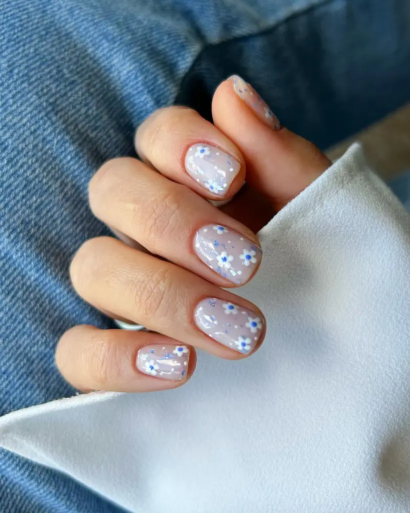 Short square nails with milky base and tiny blue and white daisy flower accents