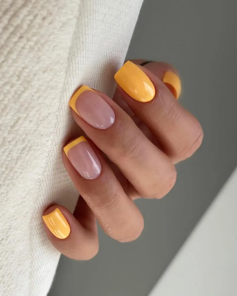 Short summer nails with alternating bright yellow polish and neutral base with yellow French tips