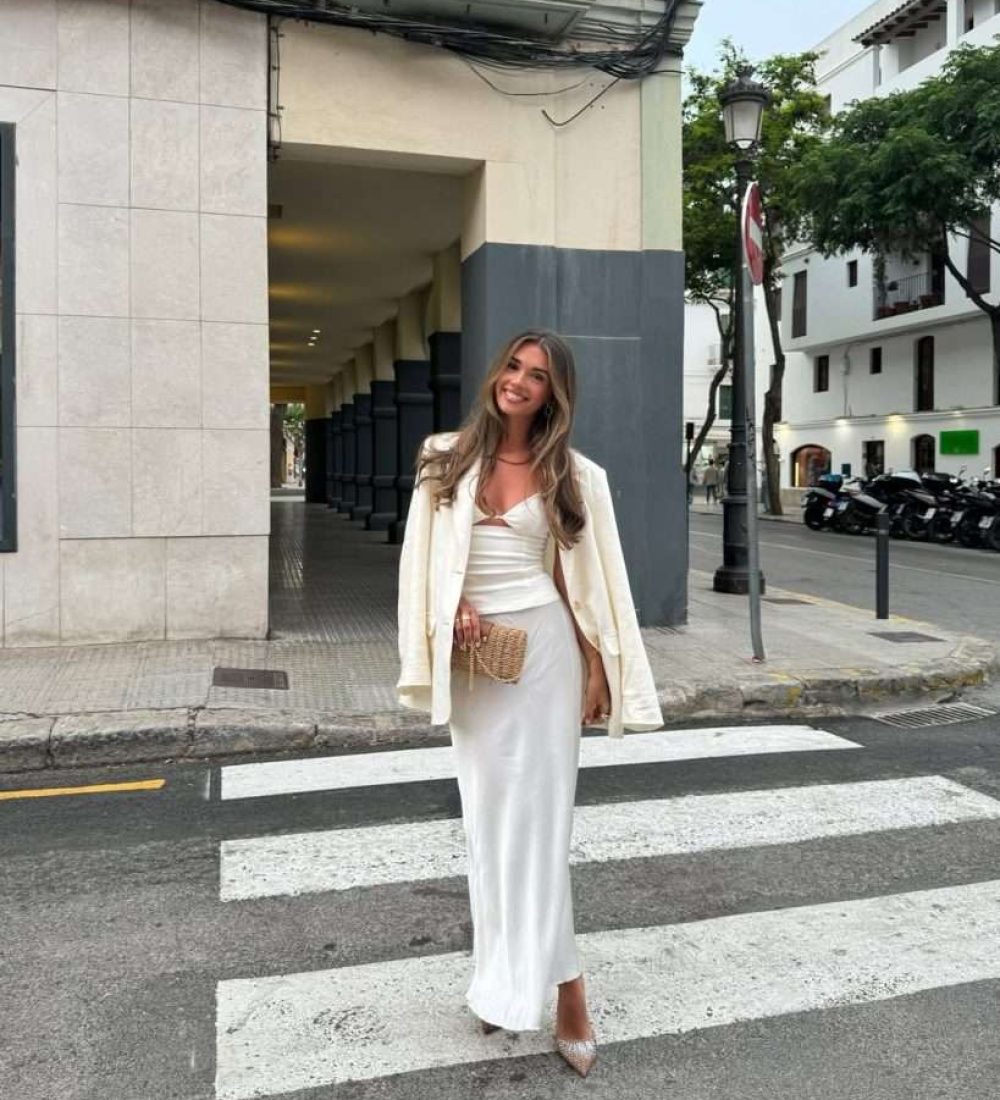 Romantic spring date night outfit with cream blazer, white silky top, matching skirt, straw clutch and sparkly pointed heels