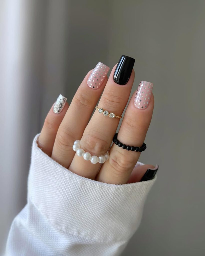Square graduation nails with black accent nail, pink base with silver polka dots, and silver glitter accent