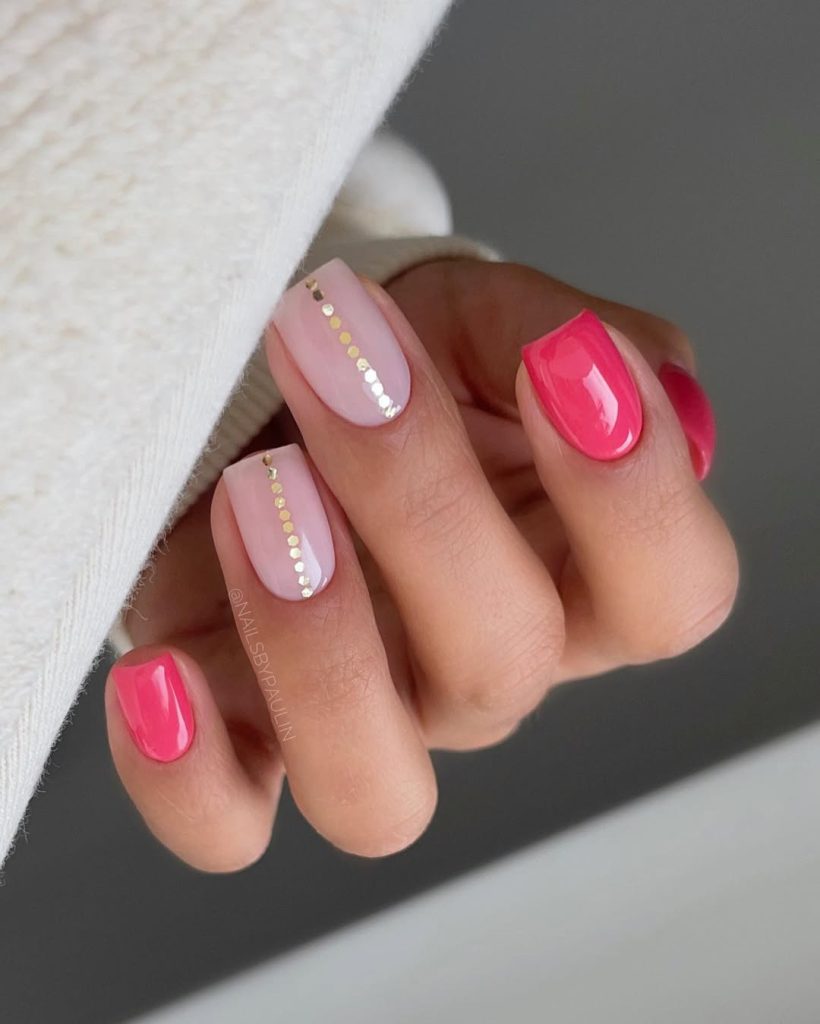 Short square nails with alternating hot pink and soft pink with vertical gold sequin stripe accents