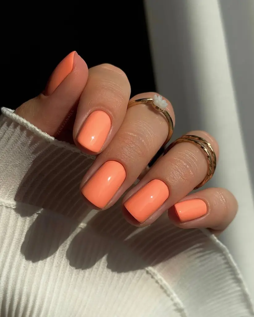 short summer nails with uniform glossy peach coral polish creating a fresh bright monochromatic manicure