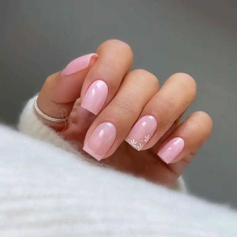 Short square nails in soft pink with white floral French tip accent on one nail