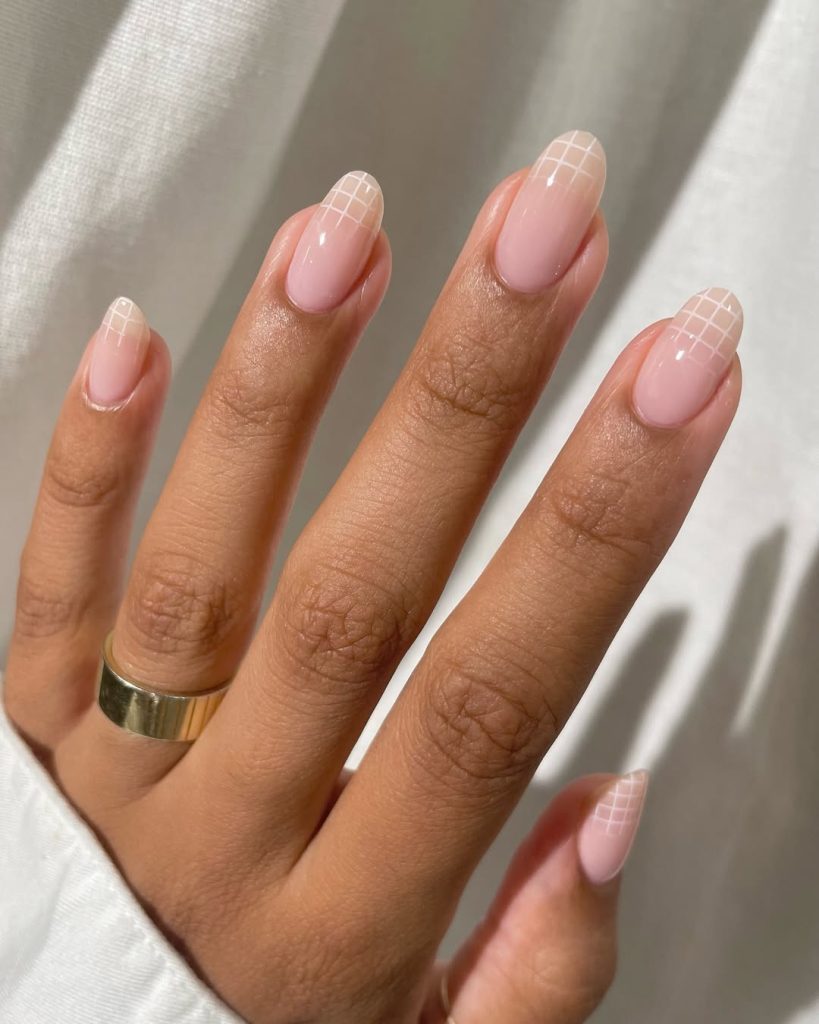  Almond-shaped minimalist nails with milky pink base and white grid pattern accent on nail tips
