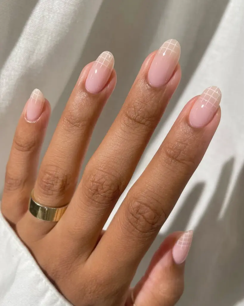 Almond-shaped minimalist nails with milky pink base and white grid pattern accent on nail tips