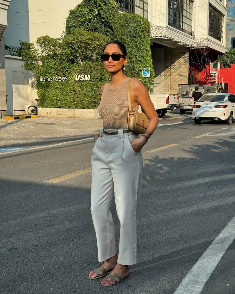 Chic summer outfit with beige knit tank top, cream wide-leg trousers, minimalist belt, olive green slides and tan crossbody bag 