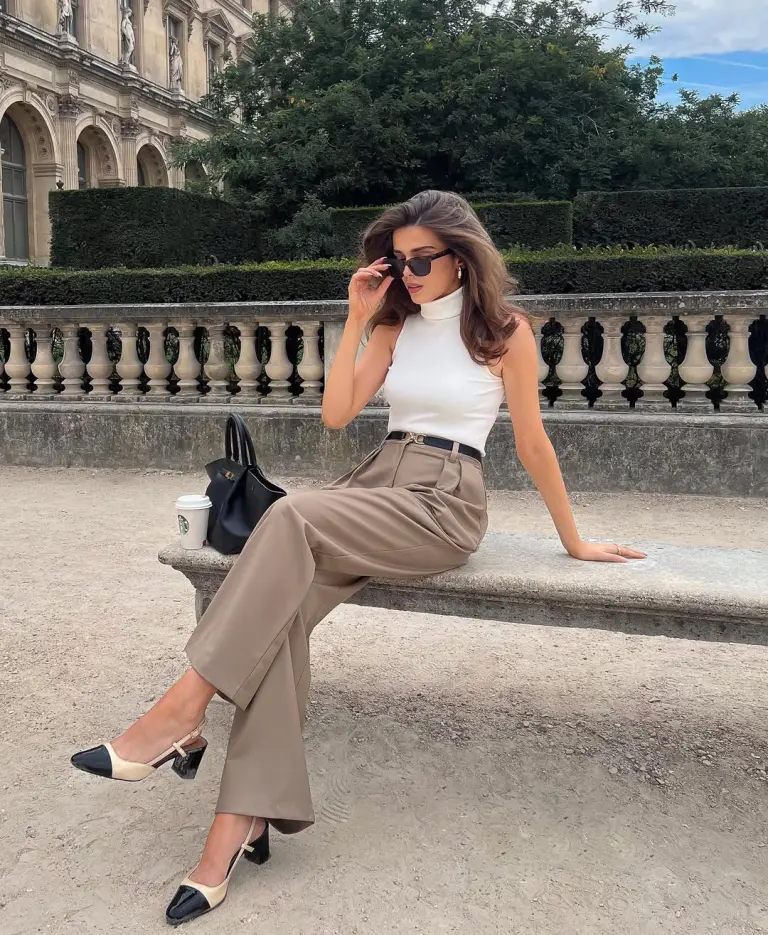 Elegant summer business casual outfit with white sleeveless turtleneck, taupe wide-leg trousers, thin black belt, black structured handbag and beige and black slingback heels