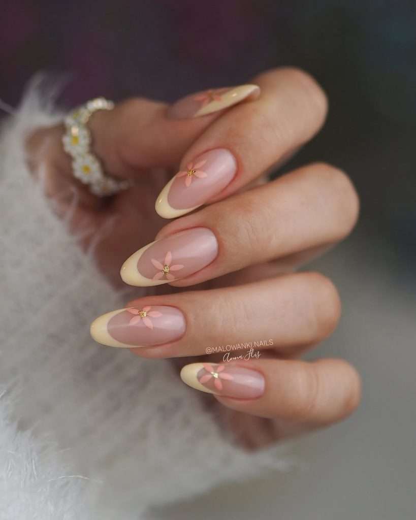 spring almond nails with pink base, cream French tips and peach flower designs with gold centers
