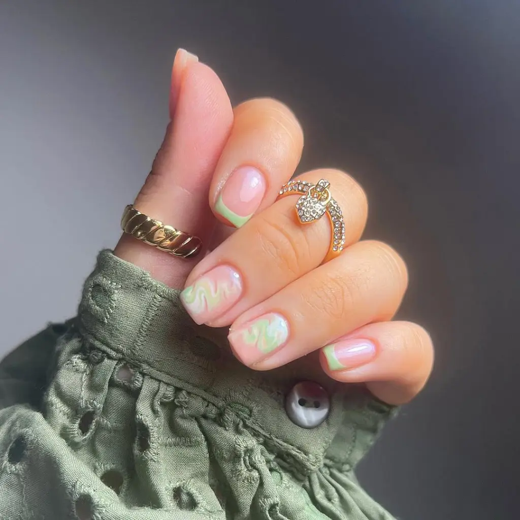 Short summer nails with clear base featuring mint green French tips and abstract pastel swirl designs on some nails