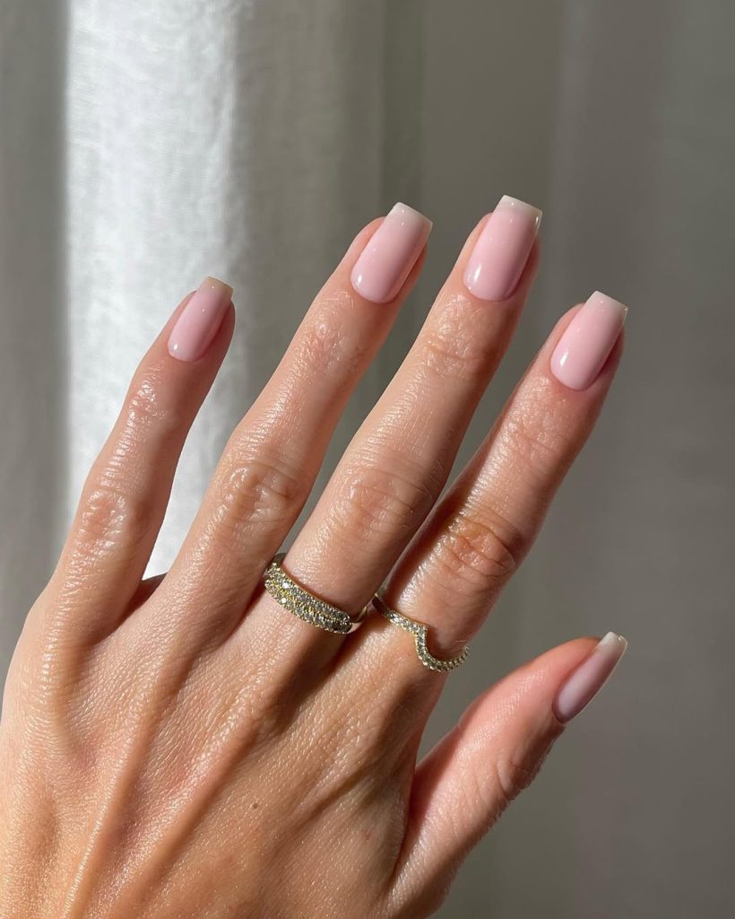 Long square minimalist nails with uniform milky pink polish in a glossy finish
