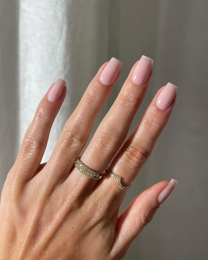 Long square minimalist nails with uniform milky pink polish in a glossy finish