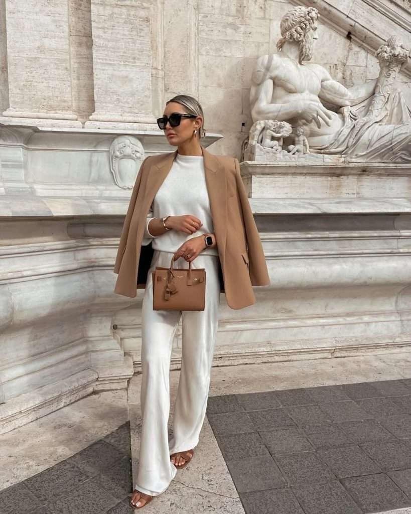 Elegant spring outfit with camel oversized blazer, ivory sweater, cream wide-leg trousers, brown sandals and tan structured designer bag