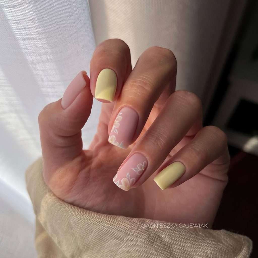 Short square nails in pink and pastel yellow with white floral accents