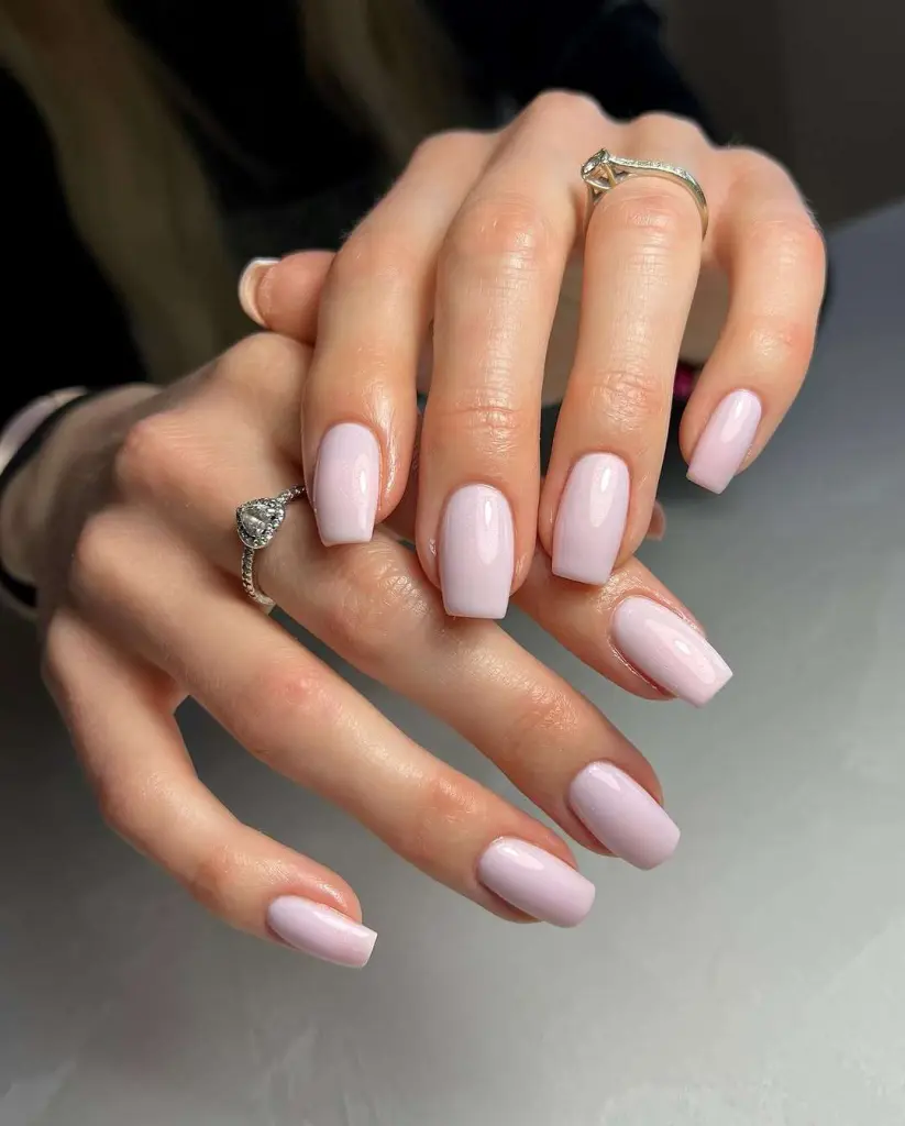 Long square nails in soft milky pink color paired with diamond rings for minimalist elegant spring manicure