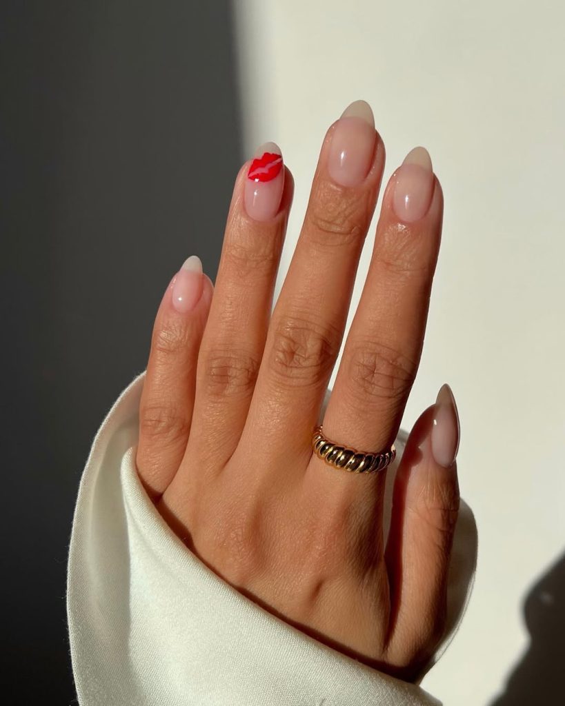 Almond-shaped minimalist nails with translucent pink base and red lip print accent on index finger
