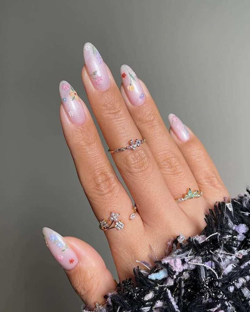 Almond shaped nails with pearlescent pink base and tiny multicolored flower designs